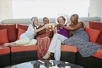 Women toasting each other with wine on urban rooftop