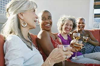 Women drinking wine together on urban rooftop