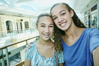 Mixed race teenage girls smiling at shopping mall