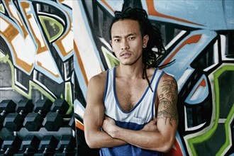 Asian man standing with arms crossed in gym