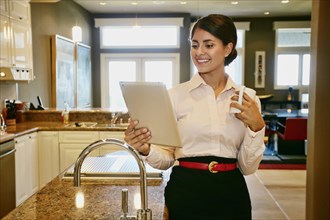 Businesswoman using digital tablet in kitchen