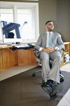 Middle Eastern businessman relaxing in chair at desk in office