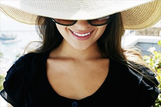 Smiling mixed race woman wearing sunglasses and sun hat
