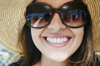 Smiling mixed race woman wearing sunglasses and sun hat