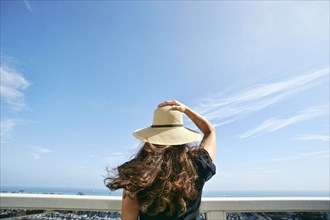 Woman in sun hat admiring scenic view from balcony