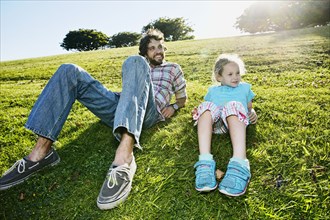 Father and daughter laying in grassy field