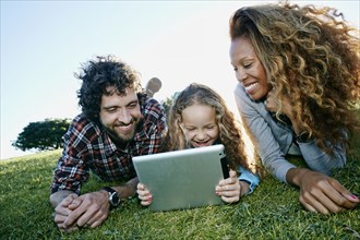 Family using digital tablet in grassy field
