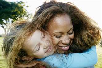 Mother and daughter hugging outdoors