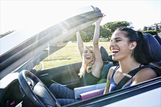 Excited women driving convertible on road trip