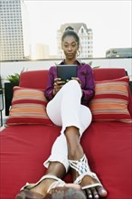 African American woman using digital tablet on urban rooftop