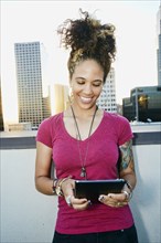 Mixed race woman using digital tablet on urban rooftop