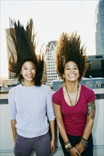 Women tossing their hair on urban rooftop
