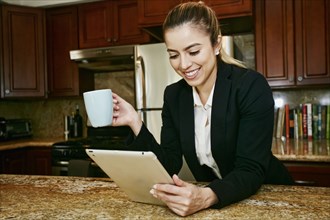 Caucasian businesswoman using digital tablet in kitchen