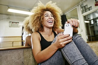 Hispanic dancer using cell phone in studio