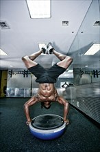 African American man doing handstand in gym