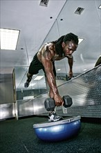 African American man lifting weights in gym