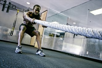 African American man working out with rope in gym