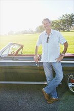 Caucasian man smiling near classic convertible