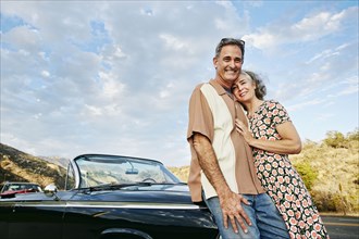Couple smiling near classic convertible