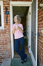 Caucasian woman drinking cup of coffee in doorway