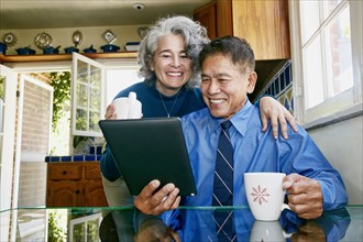 Couple using digital tablet in kitchen