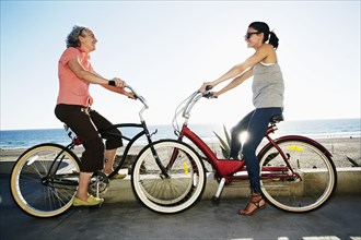 Caucasian mother and daughter riding bicycles near beach