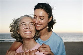 Caucasian mother and daughter hugging at beach