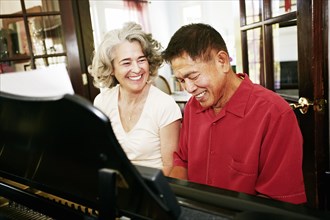 Couple playing piano together in living room