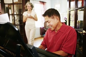 Woman watching husband playing piano in living room