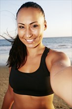 Mixed race woman taking cell phone selfie on beach