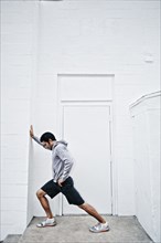 Mixed race man stretching in doorway