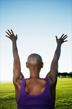 African American woman with arms outstretched in park