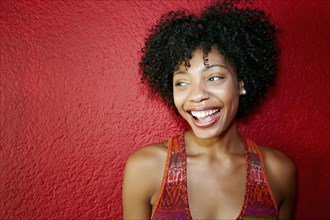 Smiling black woman standing near red wall