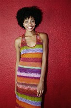 Smiling black woman standing near red wall