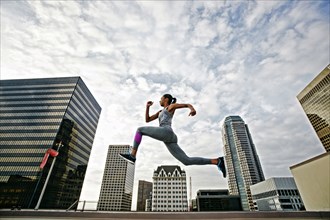 African American woman leaping on urban rooftop