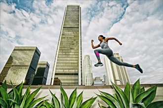 African American woman leaping on urban rooftop