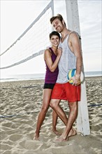 Couple hugging near volleyball net on beach