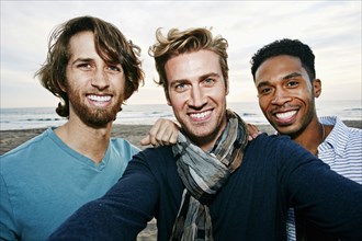 Smiling men taking selfie on beach
