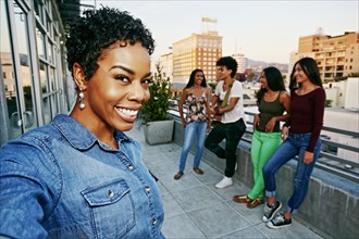 Woman smiling with friends on urban rooftop
