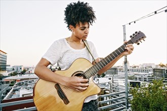Woman playing guitar on urban rooftop