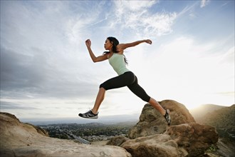 Vietnamese woman leaping on rocky hillside