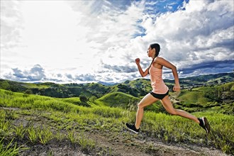 Mixed race athlete running on rural hilltop