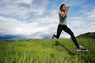 Black athlete running in rural field