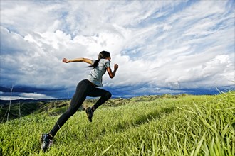 Black athlete running on rural hilltop