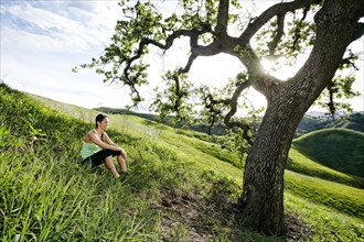 Mixed race athlete sitting on rural hillside