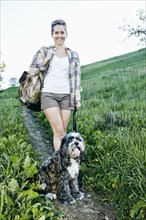 Caucasian woman walking dog on grassy hillside