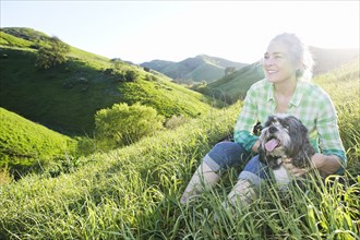 Older Caucasian woman walking dog on grassy hillside