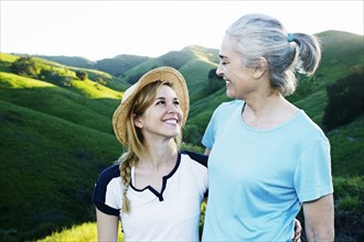 Caucasian mother and daughter smiling on rural hilltop