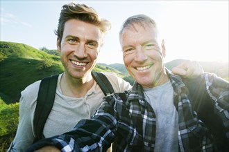 Caucasian father and son taking selfie on rural hilltop