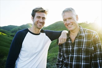 Caucasian father and son smiling on rural hilltop